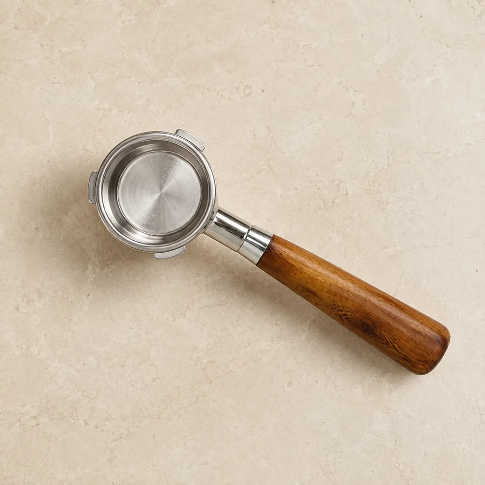 Our 58 mm bottomless portafilter seen from above on a cream stone counter: polished steel basket ring, three plain steel lugs and a conical rosewood handle